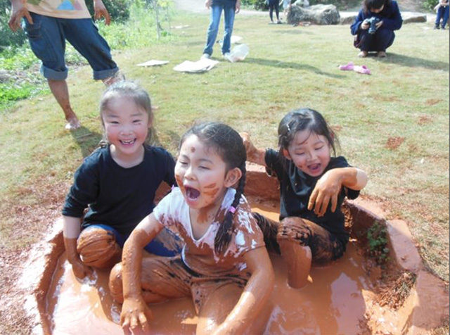 泥染めののための泥に入って遊ぶ子どもたち